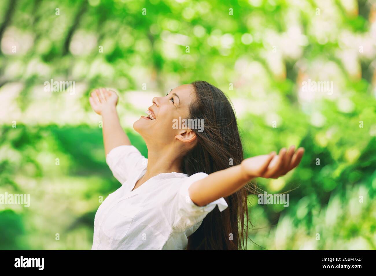 Donna felice respirare aria fresca pulita all'aperto foresta naturale per la stagione primaverile allergie polline. Ragazza asiatica spensierata con braccia distese in libertà Foto Stock