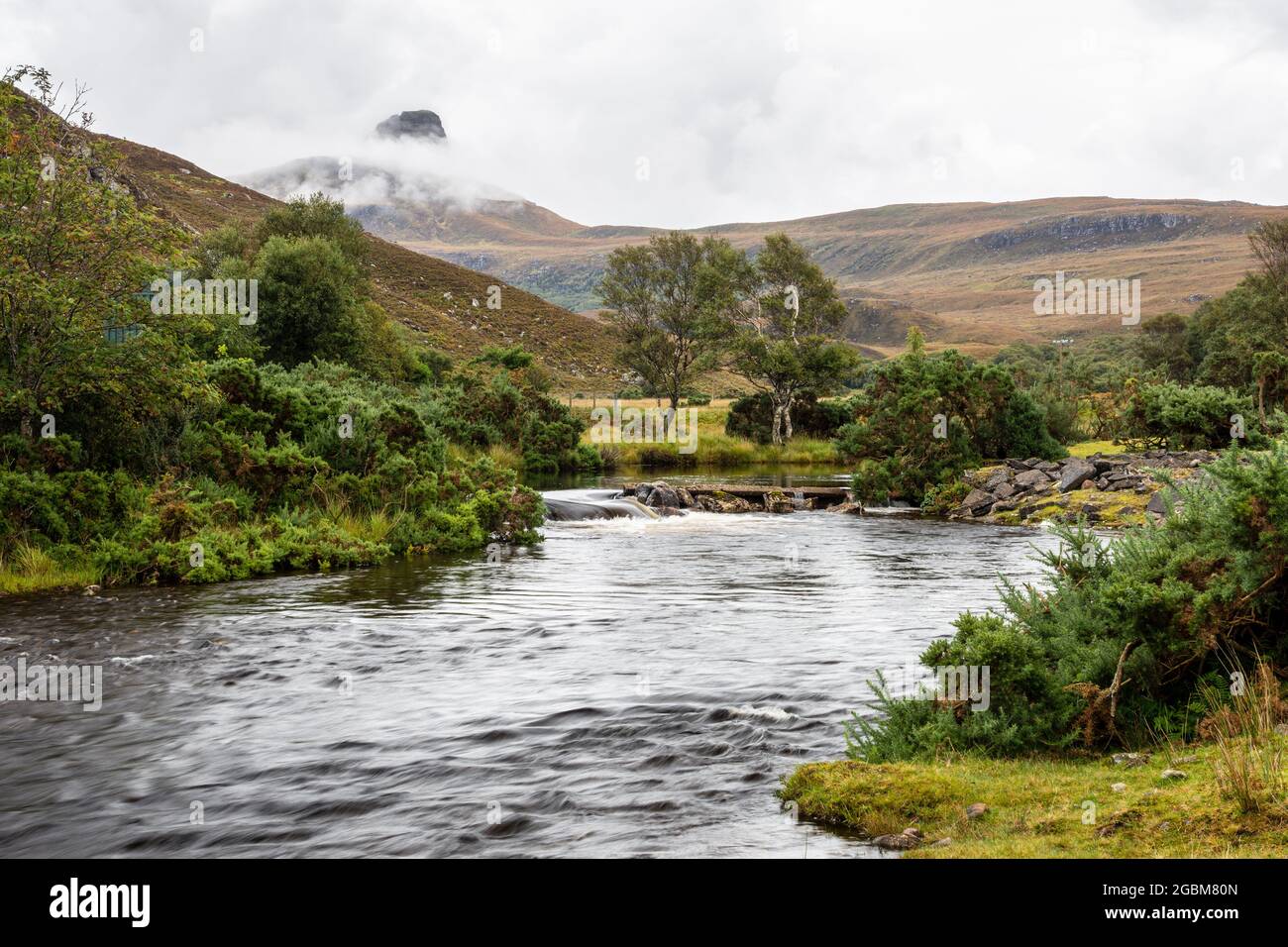 La montagna Stac Pollaidh sorge in nuvole dietro il fiume Polly in Assynt distretto di nord-ovest Highlands della Scozia. Foto Stock