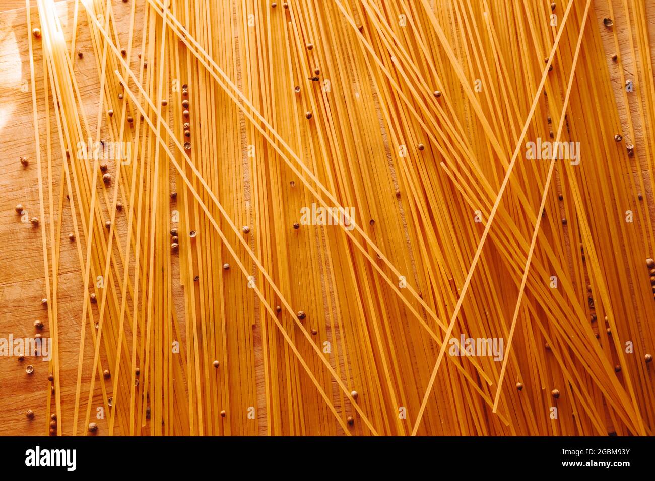 Spaghetti gialli sparsi sul tavolo con peperoni neri. Cucina italiana. Foto di alta qualità Foto Stock