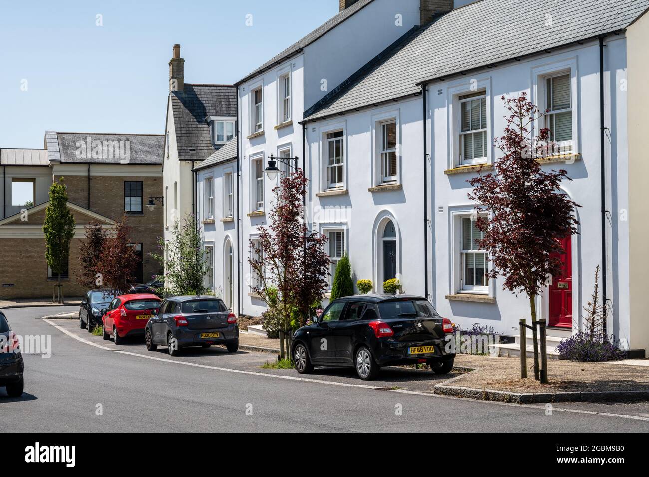 Gli alberi di strada segnano i posti di parcheggio sulla strada all'esterno delle nuove case costruite nella nuova città di Poundbury, Dorset. Foto Stock
