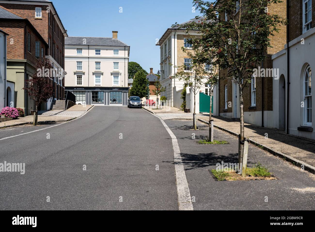 Gli alberi di strada segnano i posti di parcheggio sulla strada all'esterno delle nuove case costruite nella nuova città di Poundbury, Dorset. Foto Stock