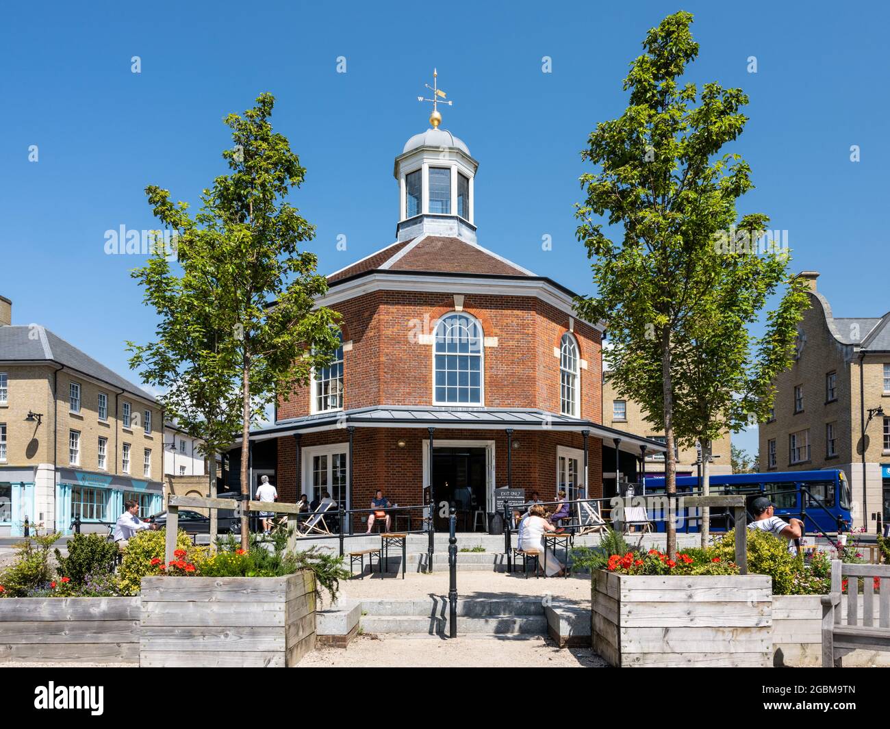 La gente siede fuori da un caffè nella piazza del Buttermarket nella nuova città di Poundbury, Dorset. Foto Stock