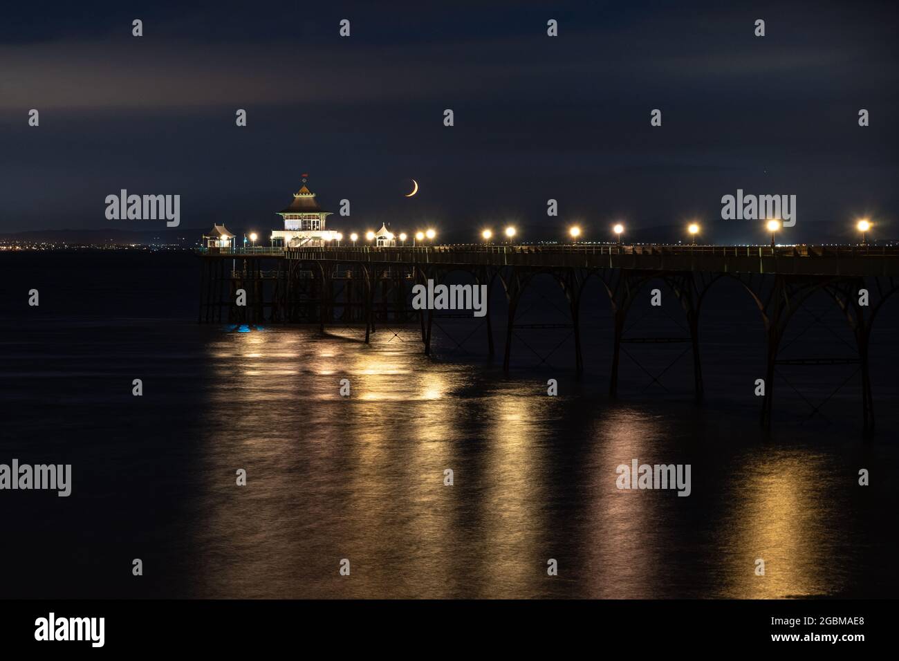 Una luna a mezzaluna si tramonta sul canale di Bristol e sul molo di Clevedon a Somerset, Inghilterra. Foto Stock