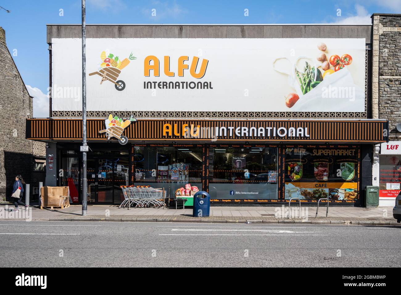 Un acquirente passa accanto a un supermercato indipendente sulla Fishponds Road, Bristol. Foto Stock