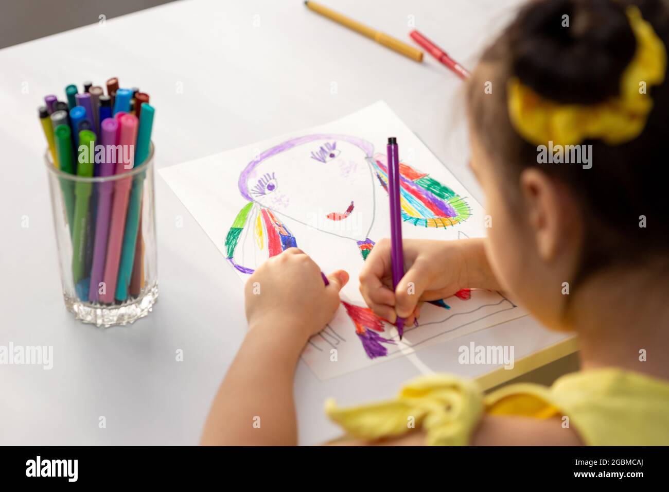 Disegno bambina brunette con pennarelli colorati. Foto Stock