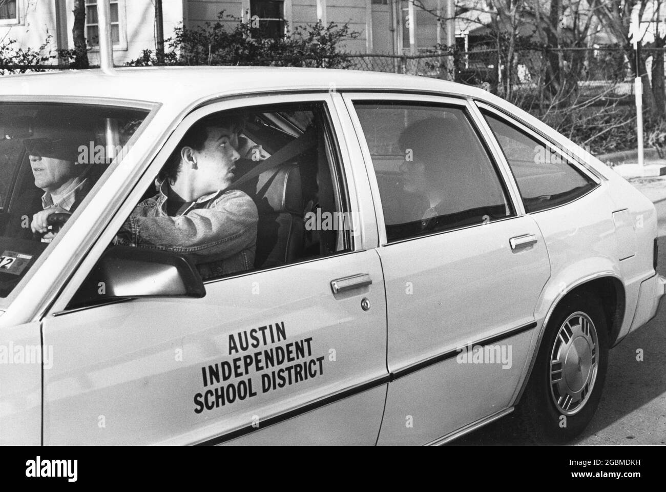 Austin Texas USA, circa 1990: Studente maschile pratica le sue abilità di parcheggio parallelo durante la classe di istruzione del conducente della scuola superiore, con istruttore seduto accanto a lui in sedile passeggero e compagno di classe seduto sul sedile posteriore. ©Bob Daemmrich Foto Stock