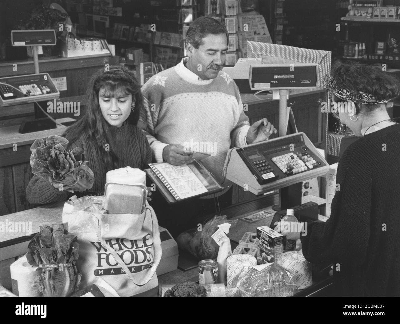 Austin Texas USA, circa 1990: Famiglia ispanica al checkout corsia di negozio di cibo salute locale Whole Foods. DISPONIBILE A colori MR ES-0437. ©Bob Daemmrich Foto Stock
