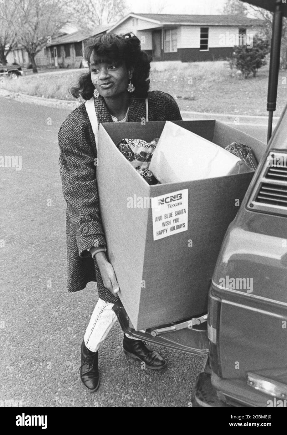 Austin Texas USA, circa 1990: Il volontario consegna scatola di regali di Natale alla famiglia a basso reddito attraverso il programma annuale Blue Santa del Dipartimento di polizia di Austin. ©Bob Daemmrich Foto Stock
