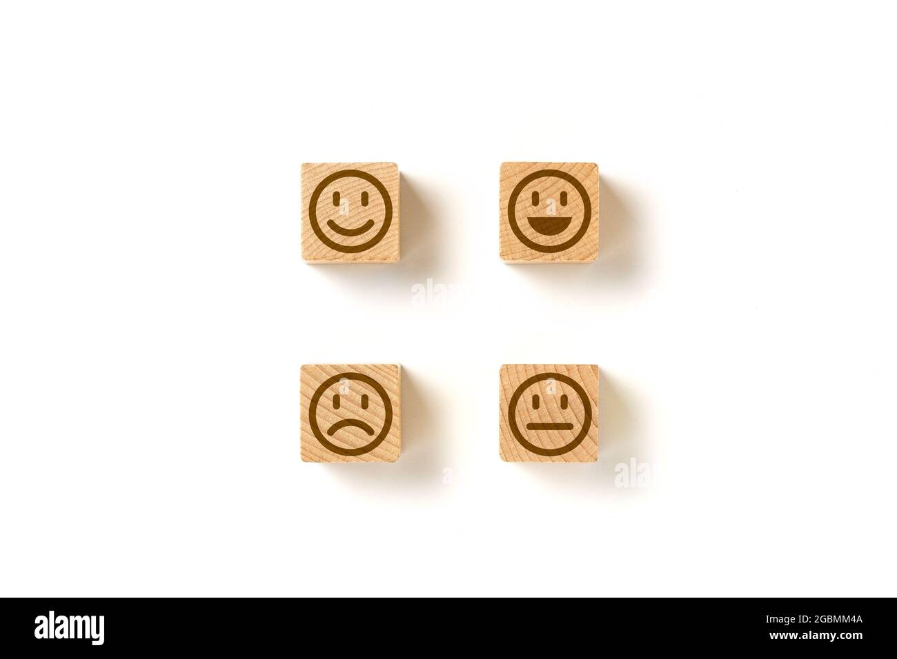 Emoticon facce in blocchi di legno su sfondo bianco. Valutazione del servizio e analisi della soddisfazione. Arrabbiato, neutro, buon umore e felice. Copia Foto Stock