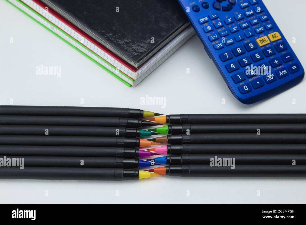 gruppo di strumenti scolastici con notebook, pennarelli, penne e calcolatrice pronti per il ritorno a scuola su sfondo bianco Foto Stock