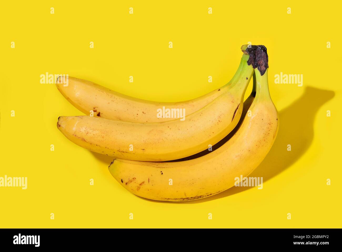 Banane con un'ombra netta isolata su sfondo giallo. Concetto di cibo. Spazio di copia per la progettazione o la modifica Foto Stock