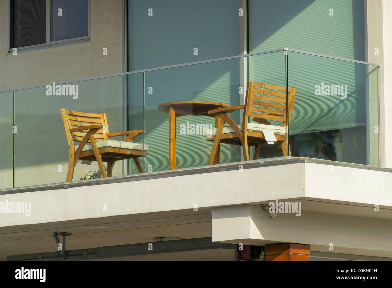 Guardaroba di sedie in legno e tavolo con balcone in vetro supportato Foto Stock