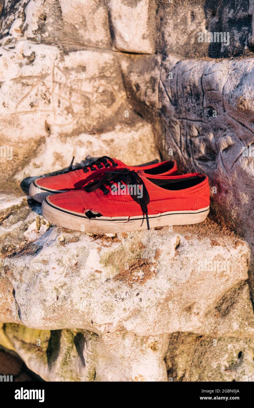 Vecchie scarpe rosse rotte su una roccia sulla costa del mare Foto stock -  Alamy
