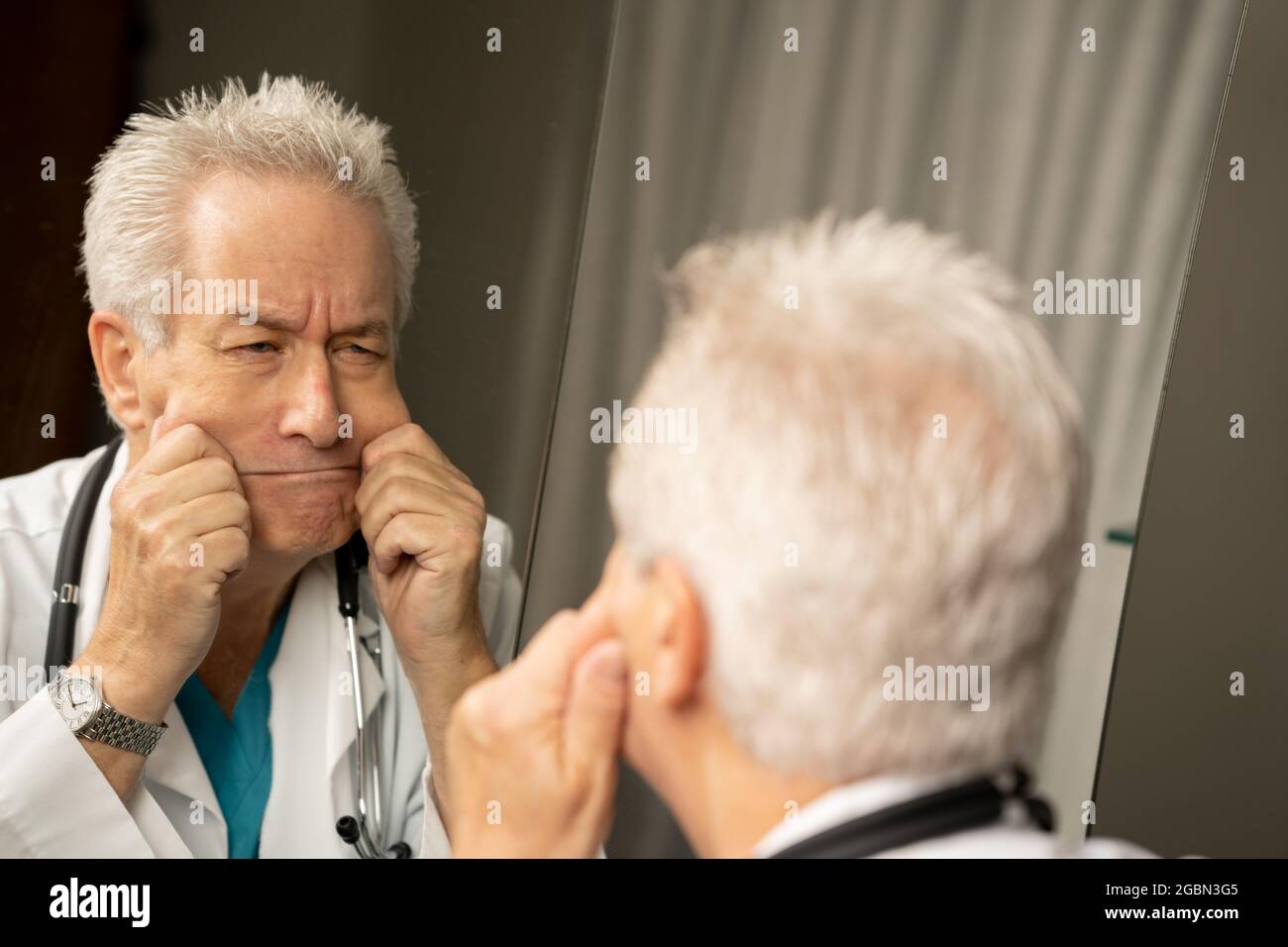 Medico che fa i volti divertenti nello specchio Foto Stock
