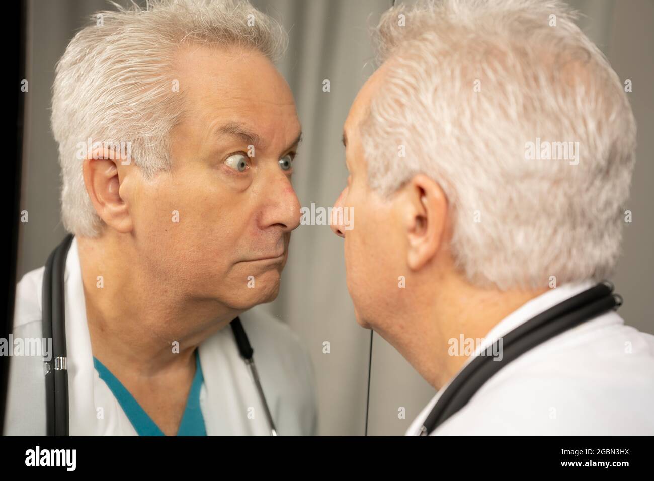 Medico che fa i volti divertenti nello specchio Foto Stock