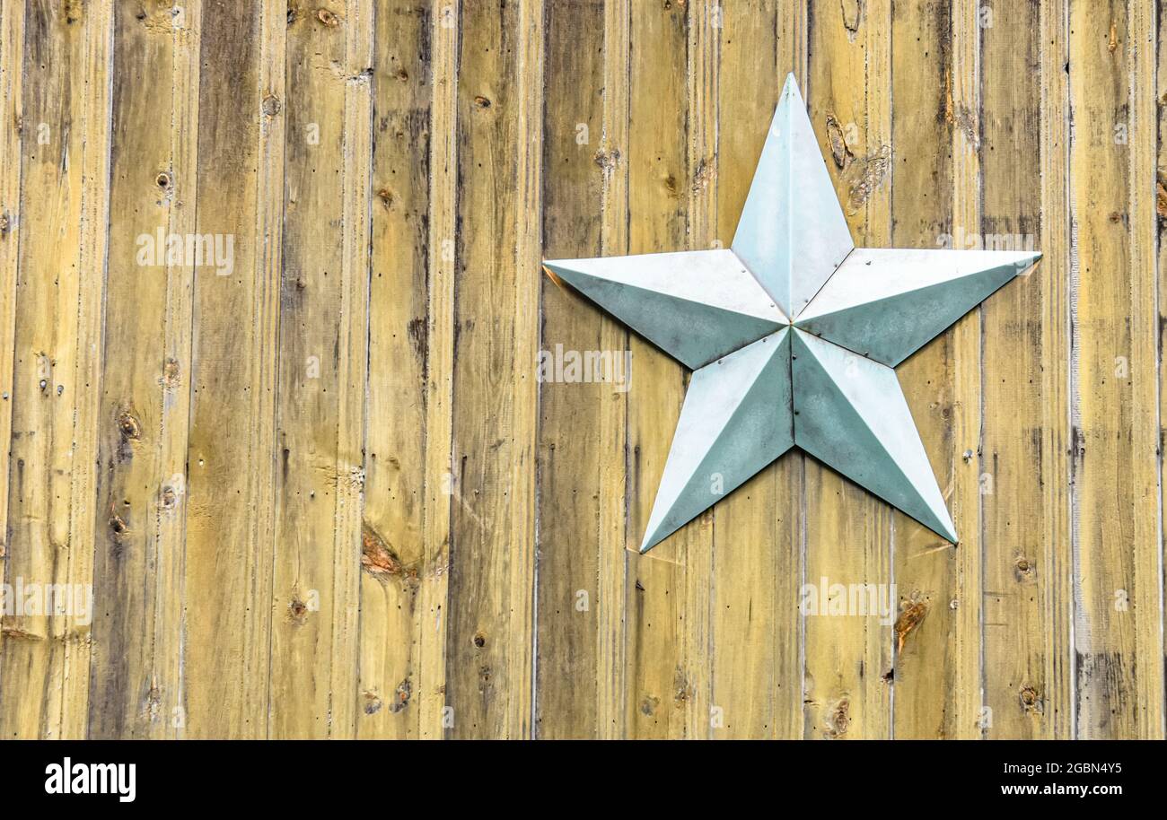 Stella di metallo blu-grigio chiaro su uno sfondo di verticale rustico legno di pino giallo. Spazio di copia. Foto Stock