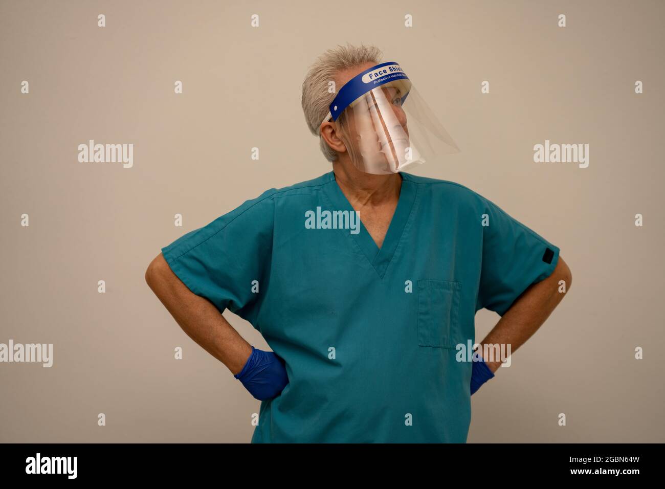Infermiere maschile con maschera di protezione viso e mani su fianchi akimbo Foto Stock
