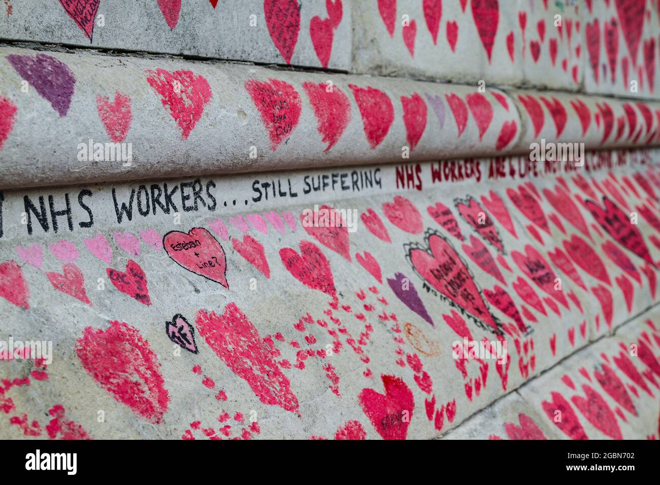 Londra, Regno Unito. 04 agosto 2021. Le parole '122,000 lavoratori del NHS ancora sofferenti' inscritte tra le migliaia di uditori sulla parete commemorativa del Covid19. Il National Covid Memorial Wall corre per circa un chilometro e mezzo lungo il fiume Tamigi, accanto all'ospedale St Thomas di Westminster. Il memoriale è iniziato intorno al 2021 aprile ed è decorato con più di 150,000 cuori rossi ciascuno rappresentante una vita persa a Covid19. Credit: SOPA Images Limited/Alamy Live News Foto Stock