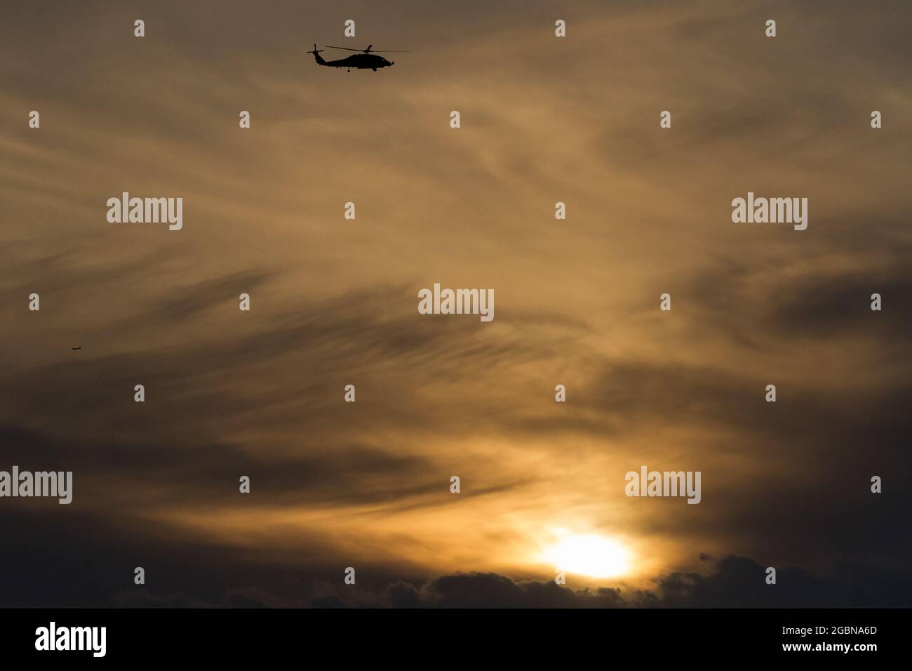 Una silhouette di un elicottero US Navy Sikorsky SH-60R Seahawk con il Maritime Strike Squadron 51 contro un cielo nuvoloso e al tramonto vicino a NAF Atsugi, Giappone Foto Stock