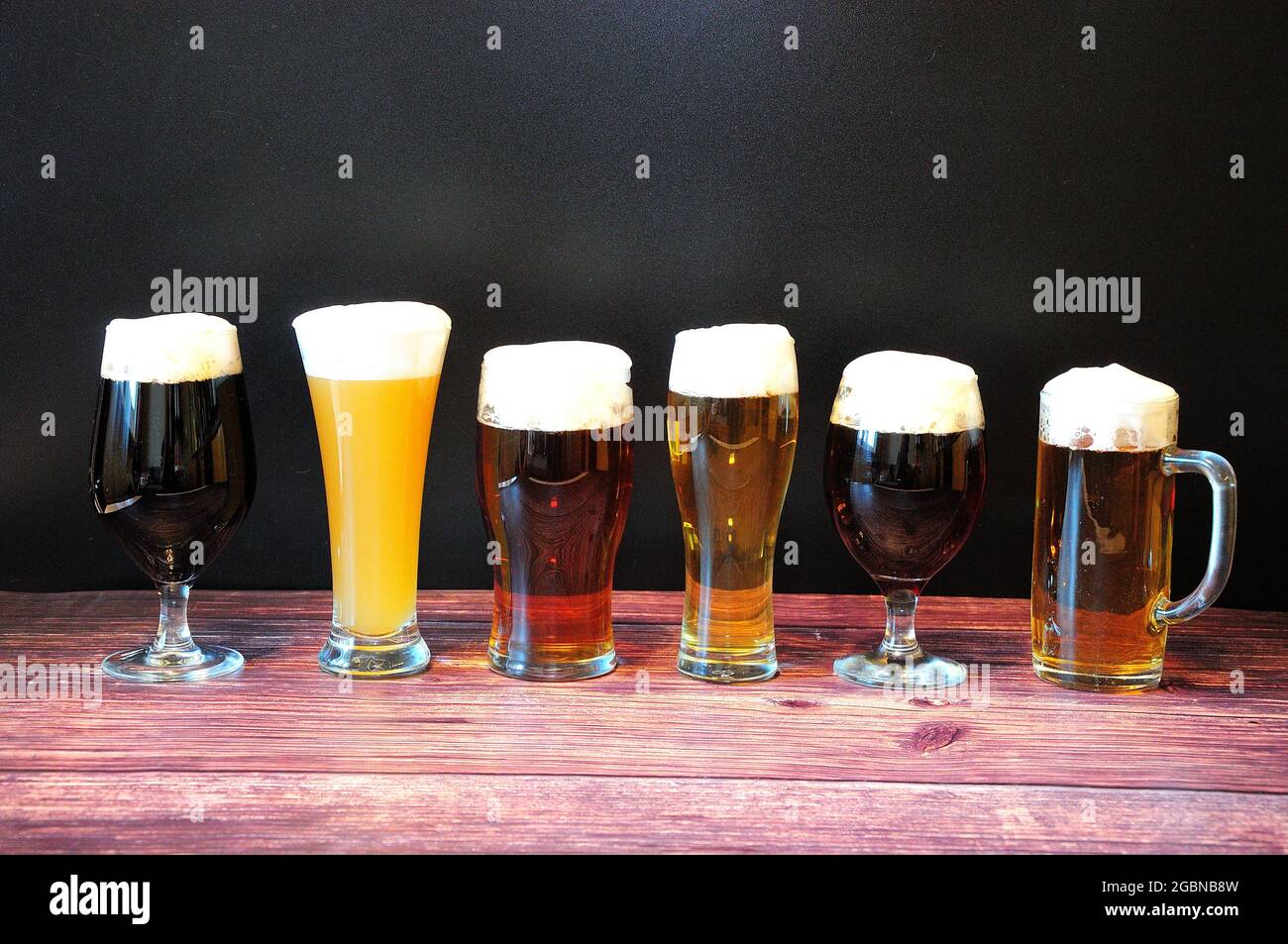 Sei bicchieri con diversi tipi di birra su un tavolo di legno. Primo piano. Foto Stock