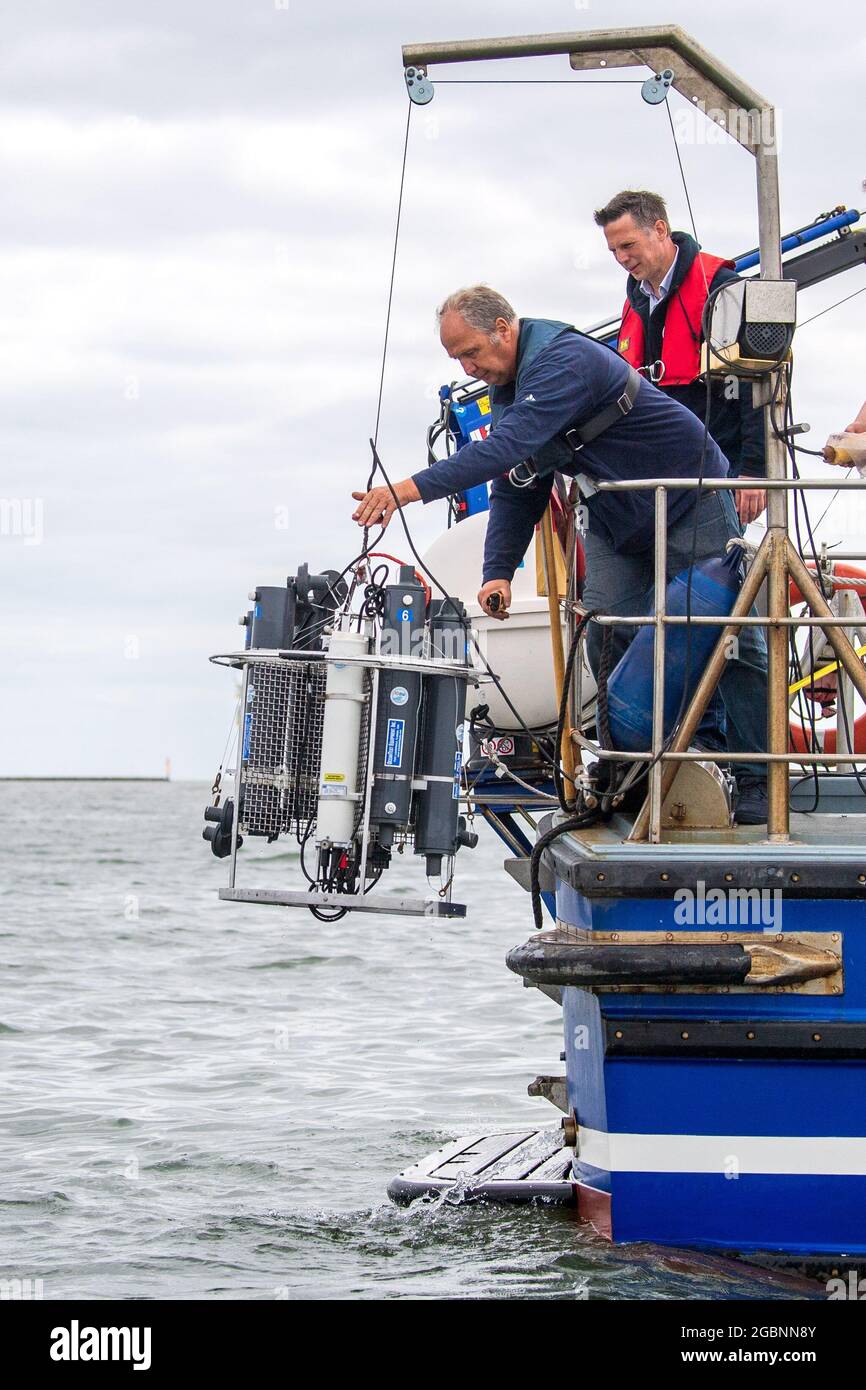 Nordsee, Germania. 22 luglio 2021. Helmo Nicolai (l) e Oliver Zielinski dell'Università di Oldenburg abbassano un dispositivo di misurazione CTD dal vaso di ricerca 'Otzum' nell'acqua. Il progetto "Good Coast" delle Università di Hannover, Oldenburg e Braunschweig mira a studiare come la protezione costiera e la protezione degli ecosistemi possano essere riconciliate e funzionare anche a lungo termine. I ricercatori utilizzano i cosiddetti laboratori reali per questo scopo. Credit: Sina Schuldt/dpa/Alamy Live News Foto Stock
