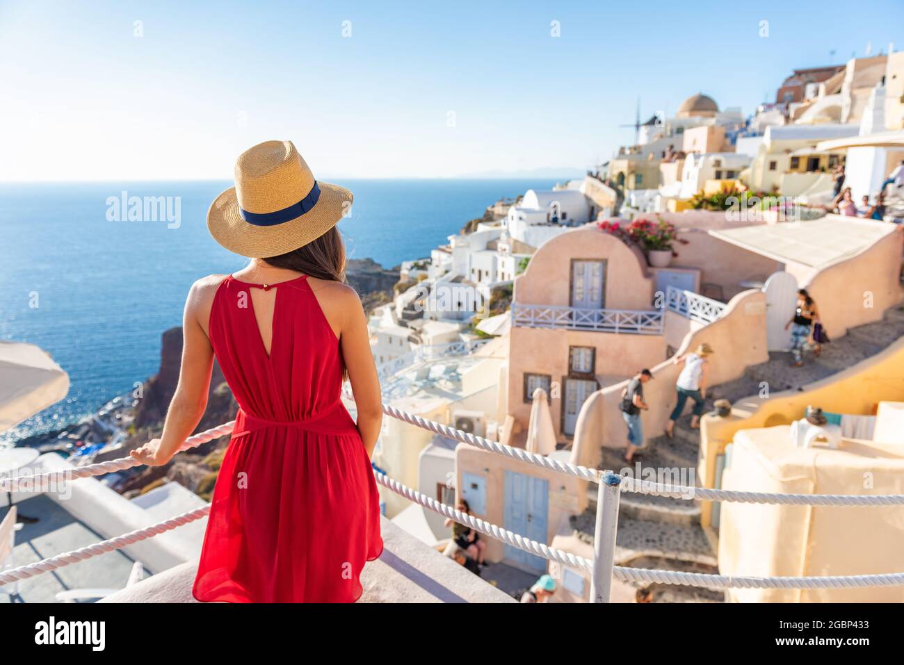 Vacanze di viaggio grecia santorini isola donna in abito rosso in viaggio in Europa guardando Oia villaggio vista, vacanza di lusso. Crociera estiva vacanze Foto Stock