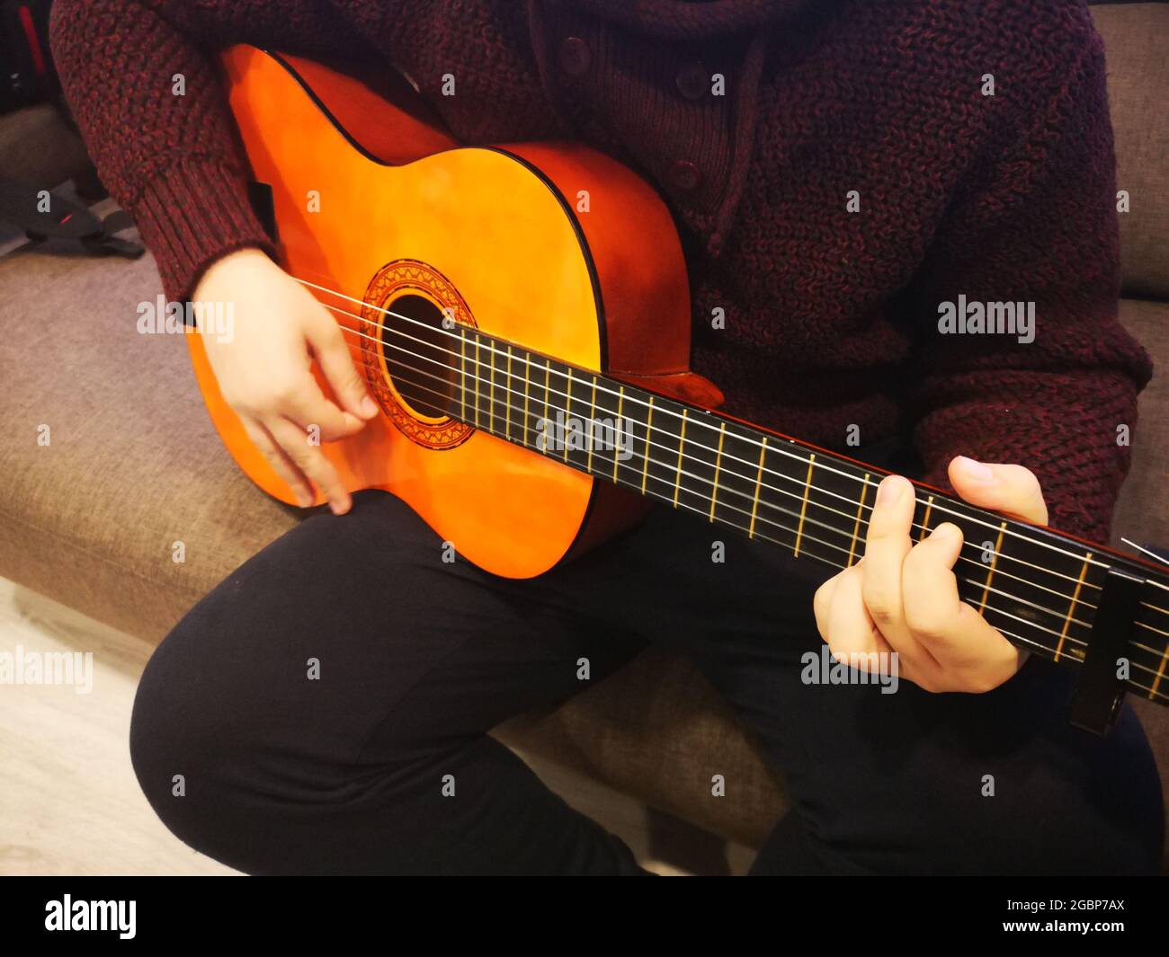 Uomo che suona la chitarra seduto sul divano Foto Stock