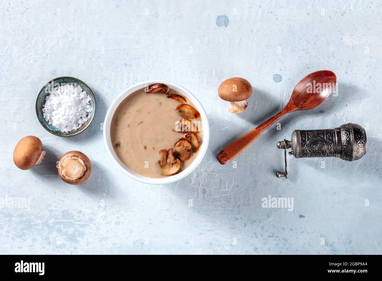 Cottura zuppa di funghi. Funghi cremini, sale, pepe, un cucchiaio di legno, un colpo di posa piatto Foto Stock