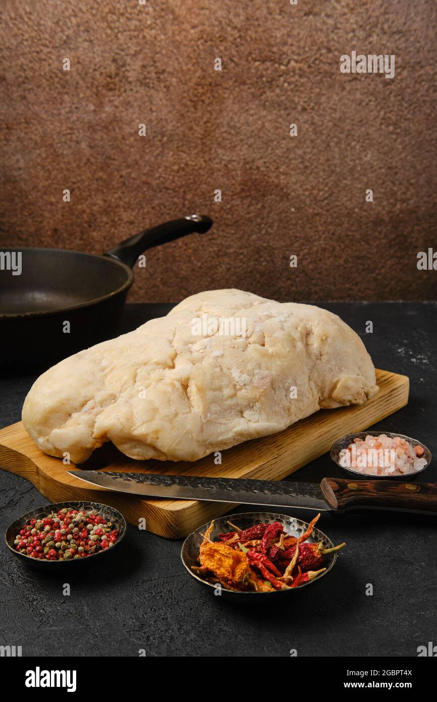 Coda di grasso di agnello sul tavolo da cucina con sale e pepe Foto Stock