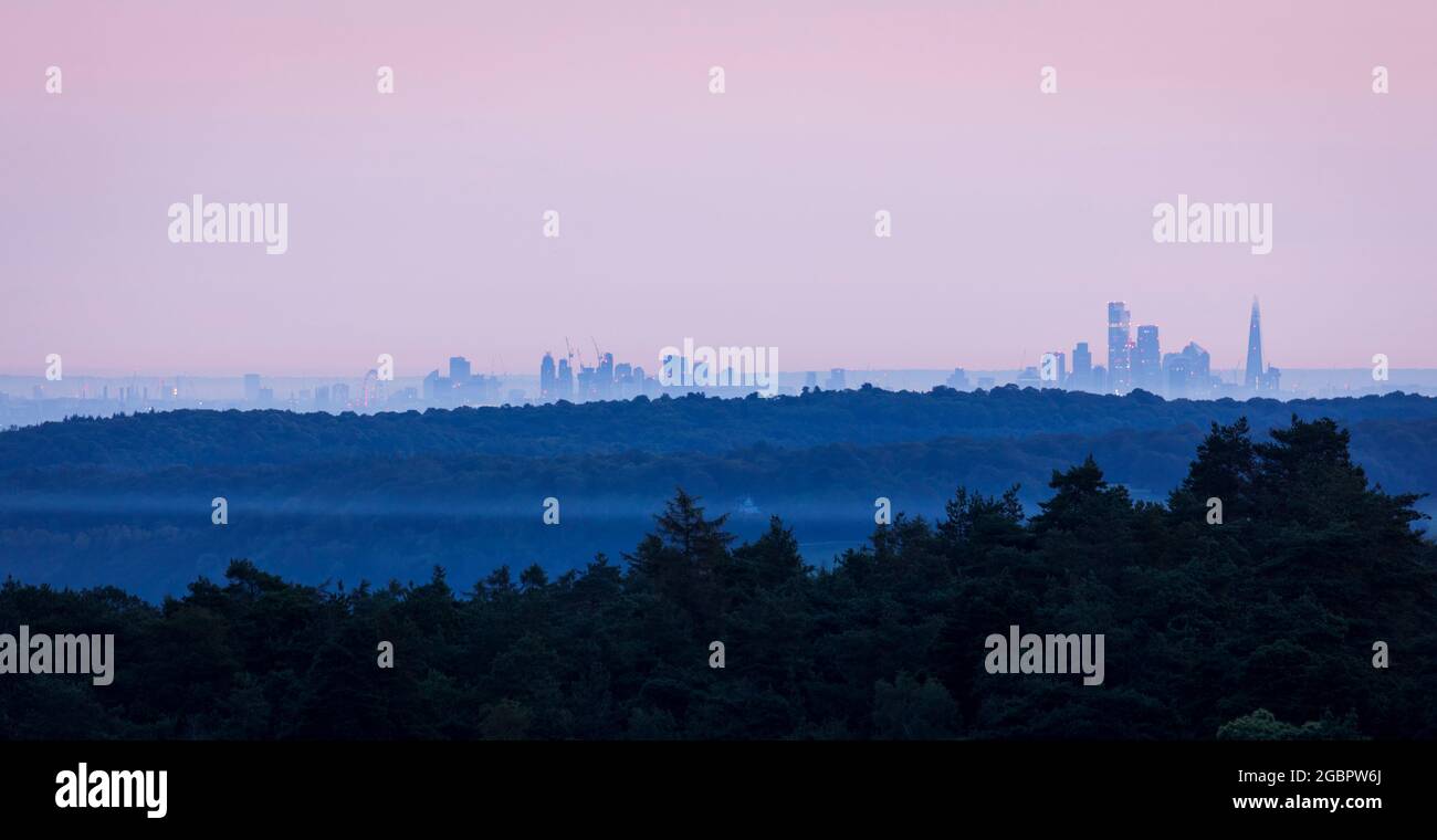 Vista dall'alba lontana dello skyline della città di Londra durante l'alba di luglio dalla cima di Leith Hill sulle Surrey Hills, Inghilterra sud-orientale Foto Stock