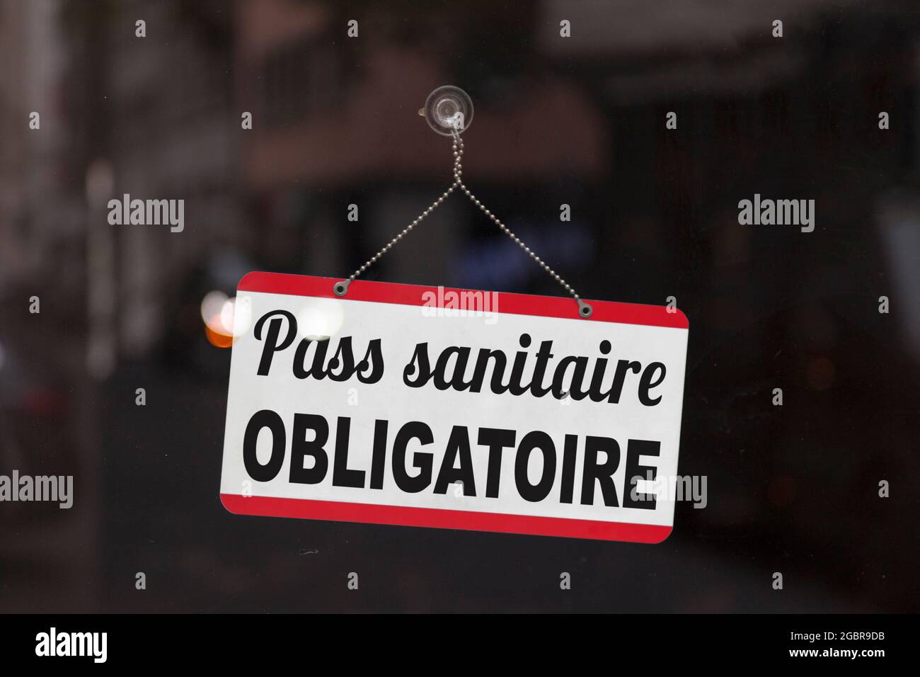 Primo piano su un segno rosso e bianco in una finestra con scritto in francese 'Pass sanitaire obligatoire', che significa in inglese 'pass sanitario obbligatorio'. Foto Stock
