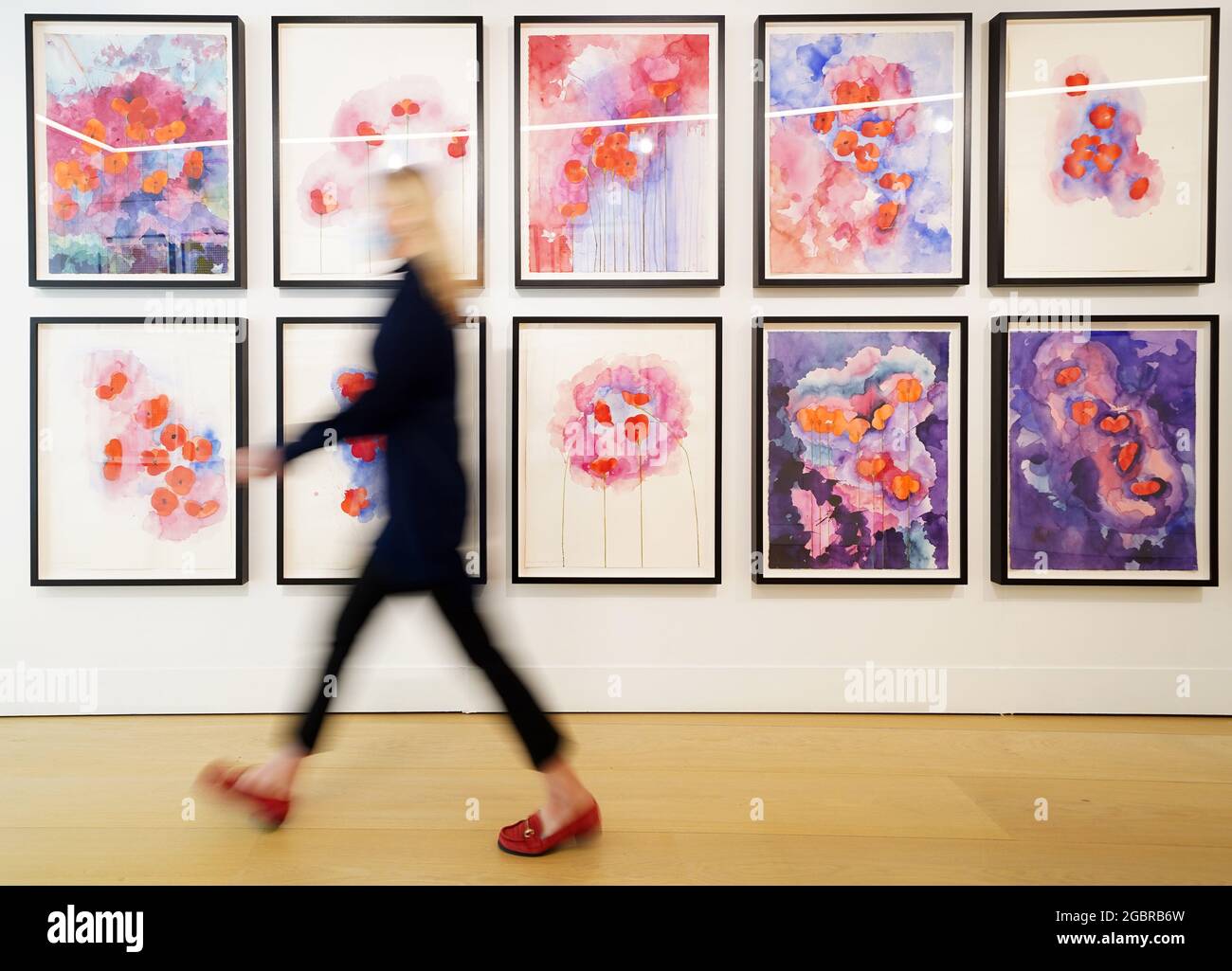 Un dipendente della galleria cammina attraverso la collezione Vesprers dell'artista Brian Clarke durante una fotocellula per la mostra presso la casa d'aste Phillips a Berkeley Square, nel centro di Londra. Il fulcro della mostra è costituito da oltre 500 acquerelli di papaveri, che Clarke ha concepito per assomigliare a un campo pieno di fiori. Data immagine: Giovedì 5 agosto 2021. Foto Stock