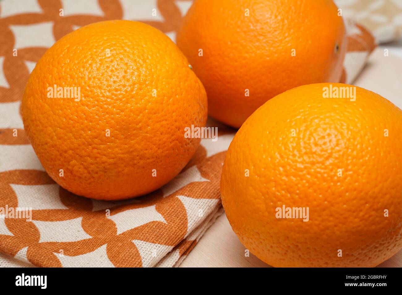 Tre arance intere di frutta su sfondo di legno. Foto Stock