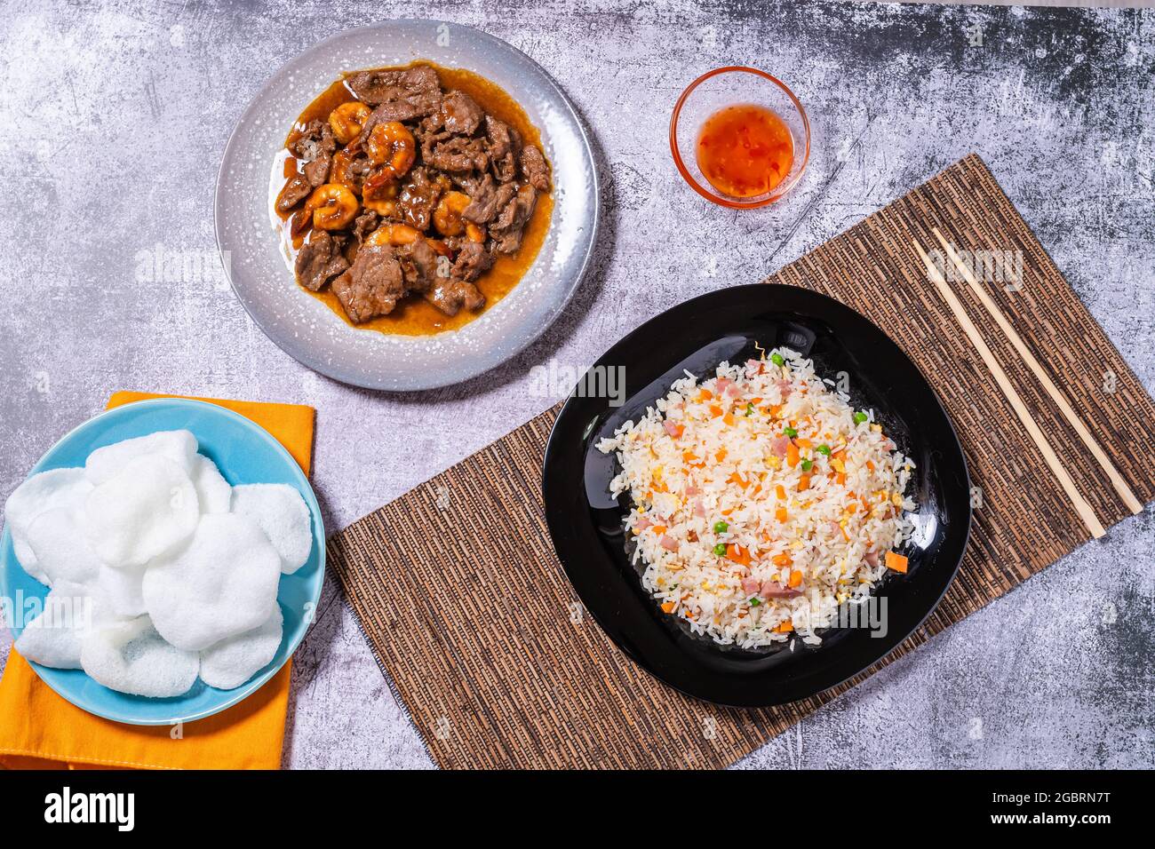 vista dall'alto di una varietà di piatti cinesi. Riso 3 delizie, manzo con gamberi, pane di gamberi e salsa dolce e acide. Cibo asiatico e orientale Foto Stock