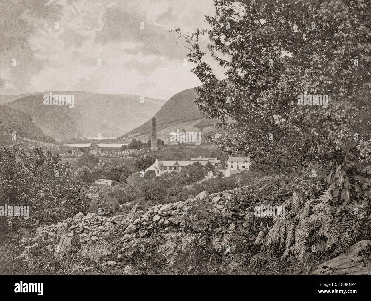 Una vista del tardo 19 ° secolo di Glendalough, una valle glaciale nella contea di Wicklow, Irlanda, rinomata per un insediamento monastico medievale, fondata nel 6 ° secolo da St Kevin, un discendente di una delle famiglie regnanti a Leinster. La remota torre rotonda, alta circa 30 metri, ha funto da punto di riferimento per i visitatori, il campanile, e talvolta come deposito e luogo di rifugio in tempi di attacco. Foto Stock