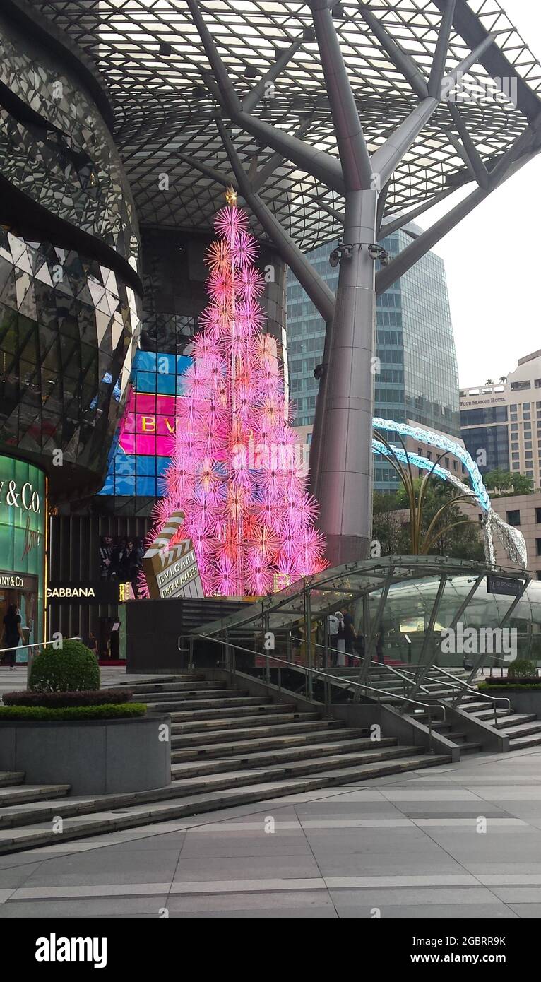 SINGAPORE, SINGAPORE - 07 Dic 2019: Un albero di Natale elettrico in rosa, illuminato di giorno di fronte ad un Mall per i migliori marchi su Orchard Road Foto Stock