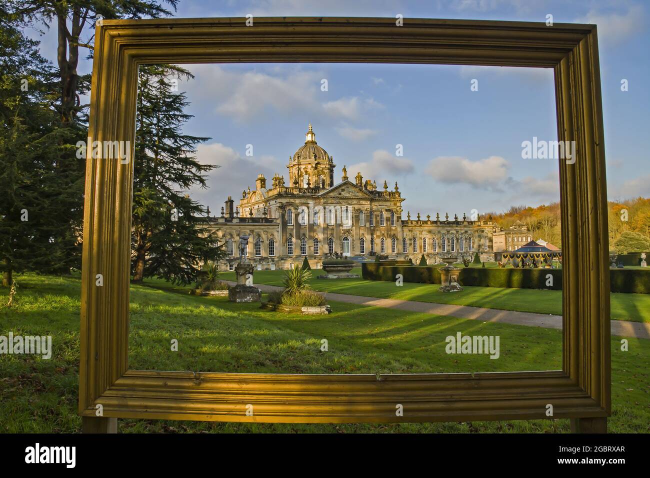 Una vista incorniciata della cupola e del fronte meridionale (giardino) di Castle Howard, North Yorkshire, Inghilterra fotografata con il sole autunnale. Foto Stock