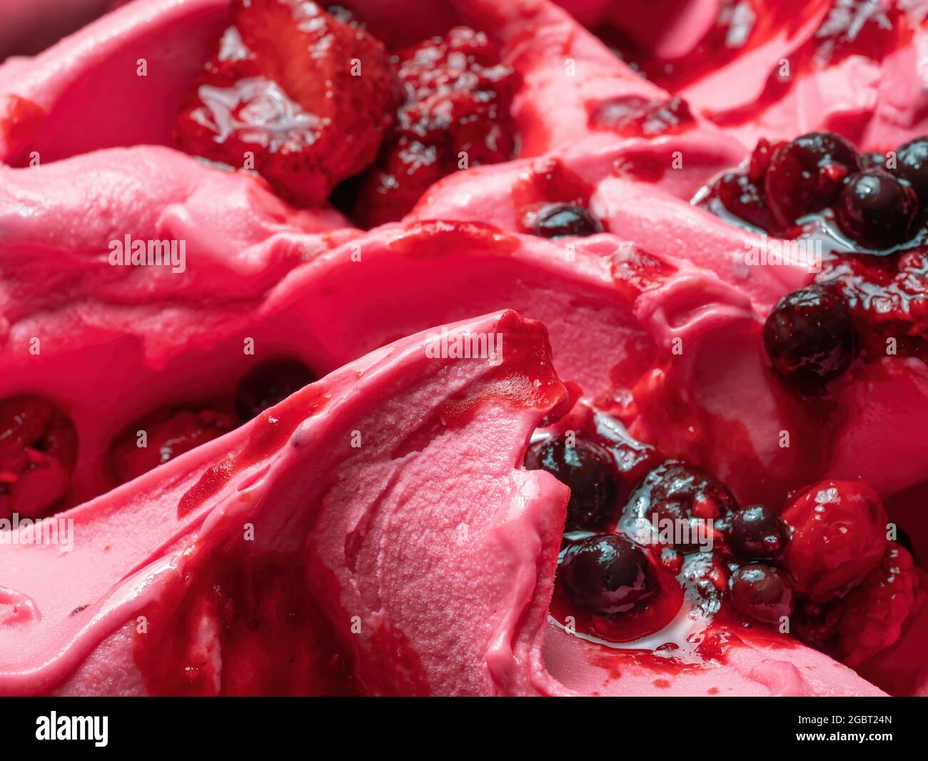 Frozen Forest Flavour gelato - dettaglio full frame. Primo piano di una superficie rosa di gelato coperto con pezzi di frutta rossa. Foto Stock