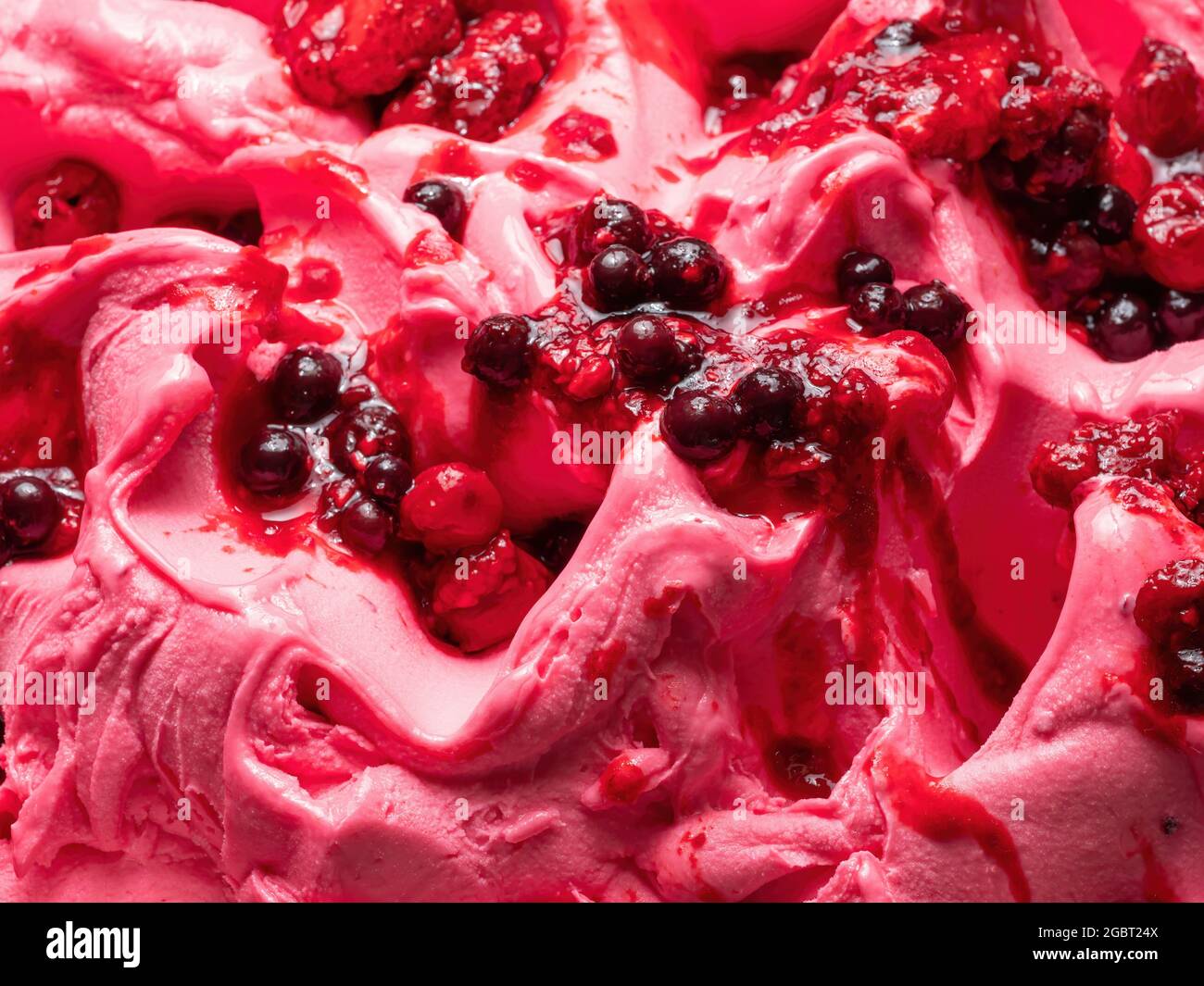 Frozen Forest Flavour gelato - dettaglio full frame. Primo piano di una superficie rosa di gelato coperto con pezzi di frutta rossa. Foto Stock