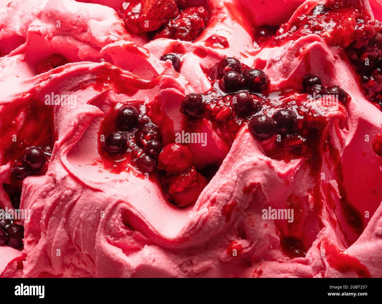 Frozen Forest Flavour gelato - dettaglio full frame. Primo piano di una superficie rosa di gelato coperto con pezzi di frutta rossa. Foto Stock
