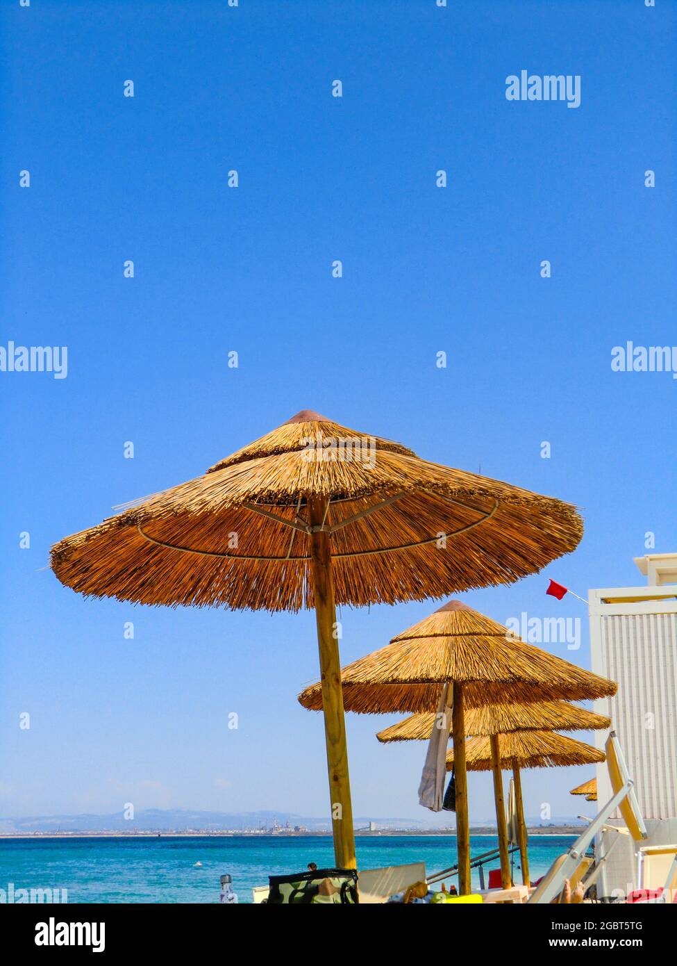 Ombrelloni di paglia di fronte al mare smeraldo e spiaggia di sabbia bianca  a Ezzi Mannu nel mese di agosto 2021, spiaggia di Pazzona, Sardegna,  Italia, Europa Foto stock - Alamy