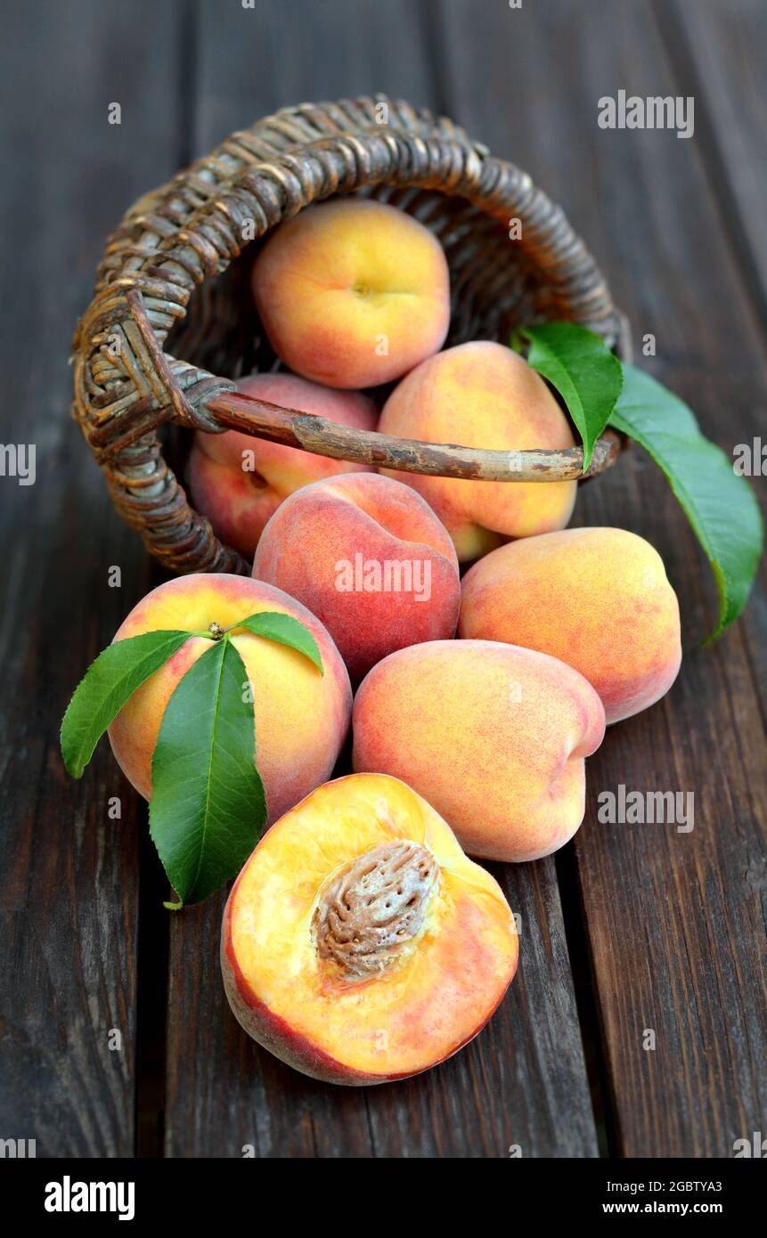 Frutta di pesca matura appena prelevata su un vecchio tavolo di legno, fuoco selettivo nella parte inferiore dell'immagine. Il concetto di giardinaggio organico. Foto Stock