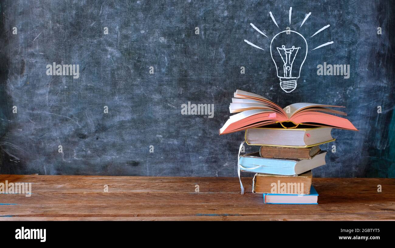 libri e lavagna con disegno di una lampadina, istruzione, apprendimento, lettura, idea, concetto di creatività, grande spazio di copia Foto Stock