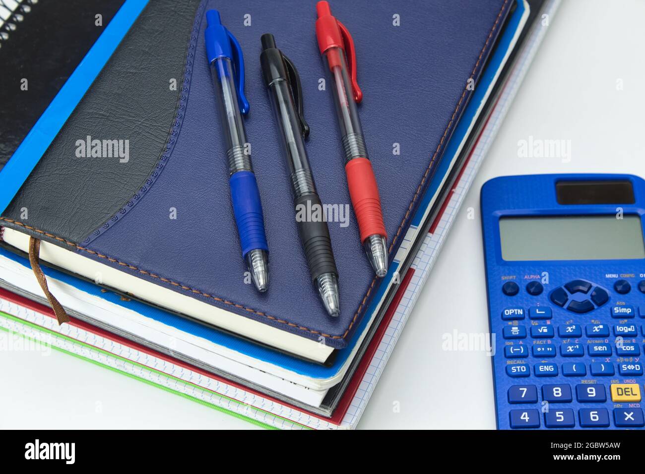 set di strumenti scolastici pronti per il ritorno a scuola con blocco note, penne, pennarelli e calcolatrice su sfondo bianco Foto Stock