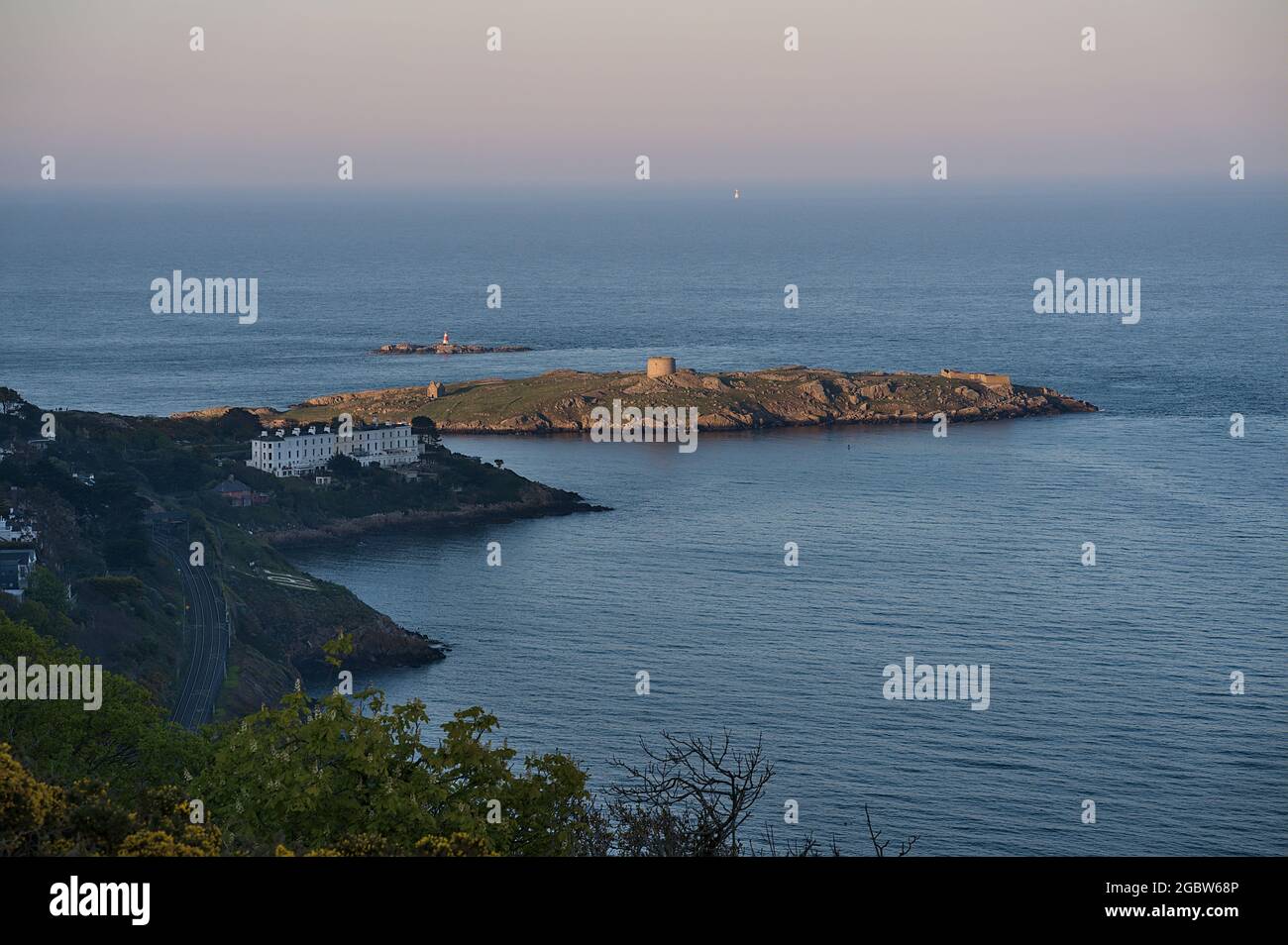 Splendida vista serale di Sorrento Point, Dalkey Island e il faro di Muglins da Killiney Hill durante l'ora d'oro, Dublino, Irlanda. Messa a fuoco morbida Foto Stock