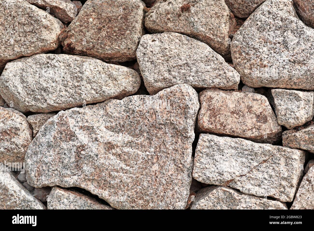 Parete con pietre grigie e marroni irregolari di diverse dimensioni e di forma Foto Stock