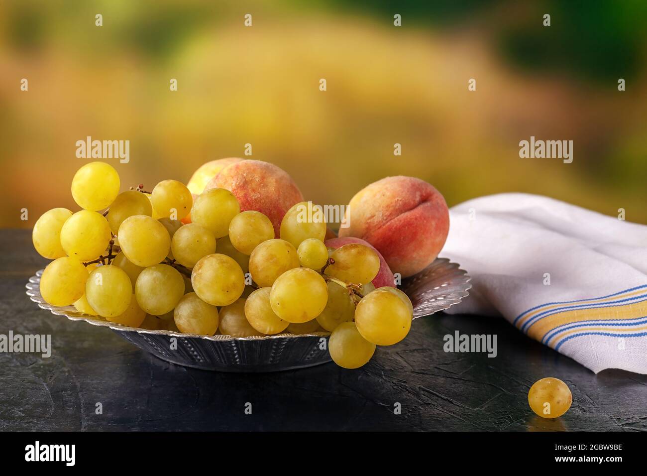 Acini e pesche maturi in una ciotola di metallo all'aperto Foto Stock