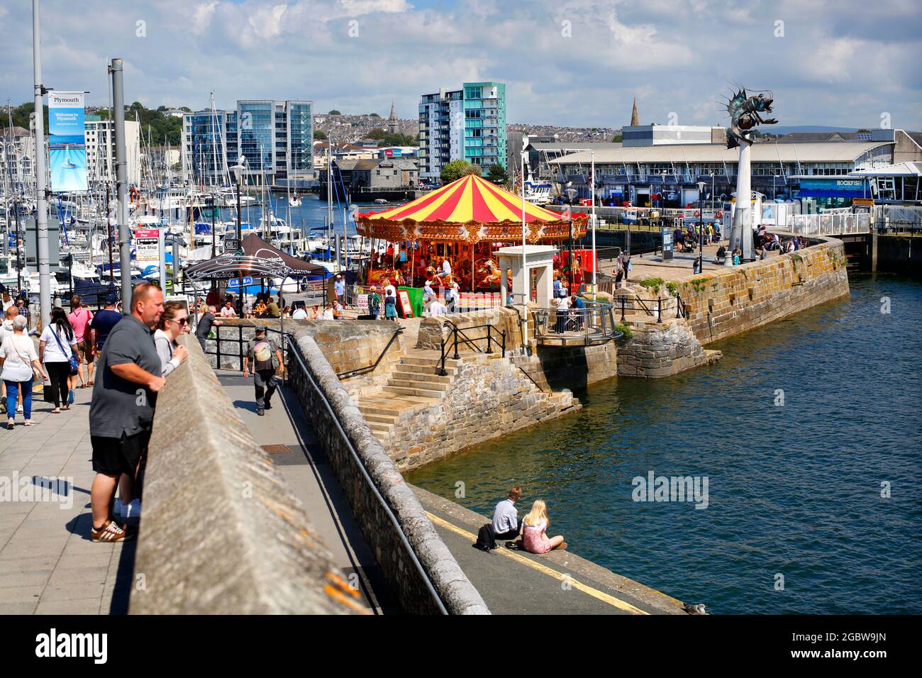 Il Barbican a Plymouth, Devon, Regno Unito. Vista verso il porto di Sutton con i gradini Mayflower visti di fronte alla giostra vittoriana. Foto Stock
