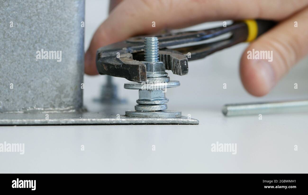 Costruttore avvitare un dado su una vite metallica e fissare saldamente una parte di un assieme meccanico Foto Stock