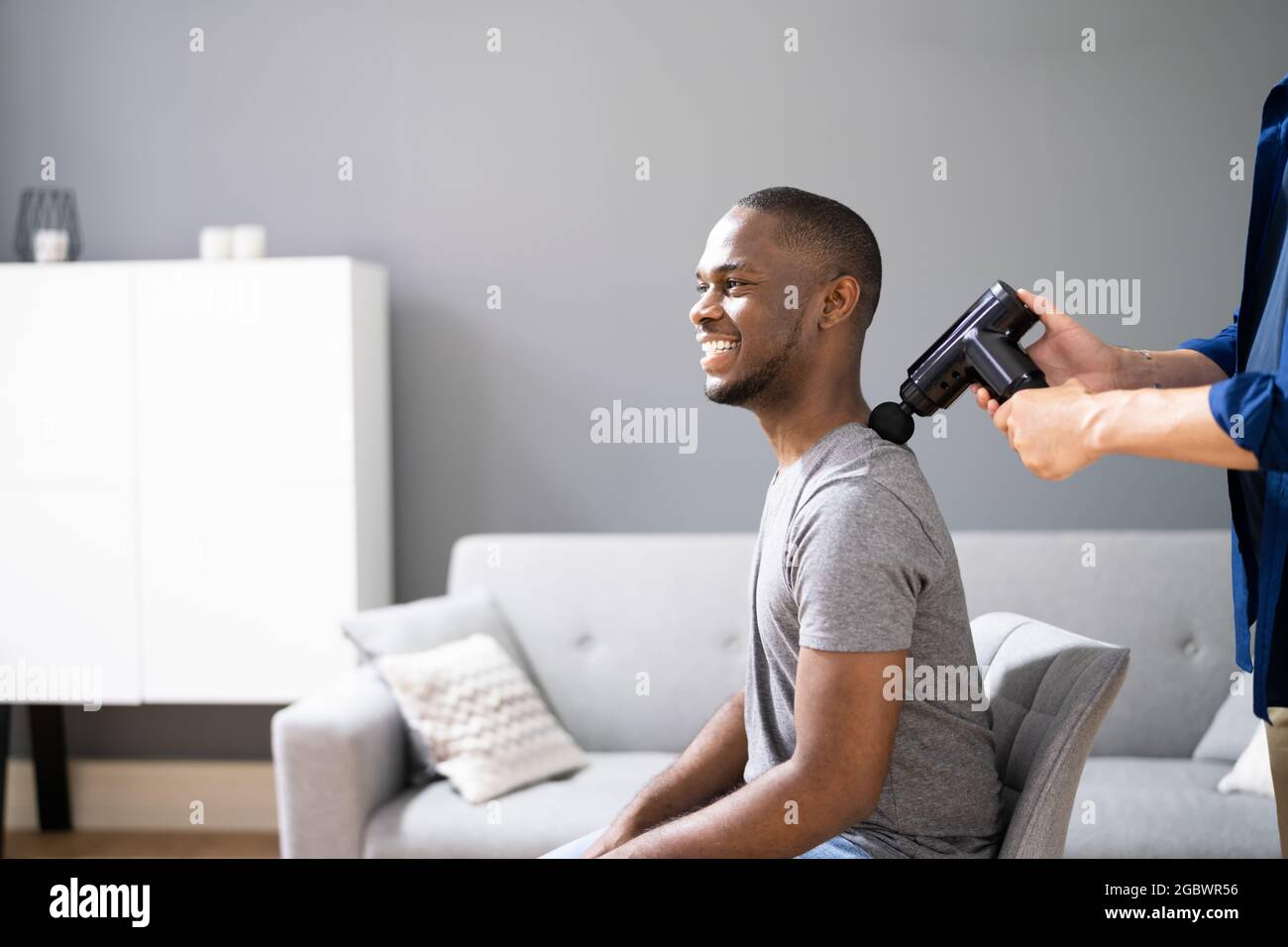 Terapia di recupero delle spalle usando la pistola di massaggio o la macchina Foto Stock